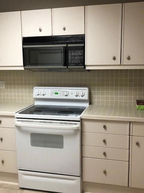 Kitchen with white electric range oven, black mic