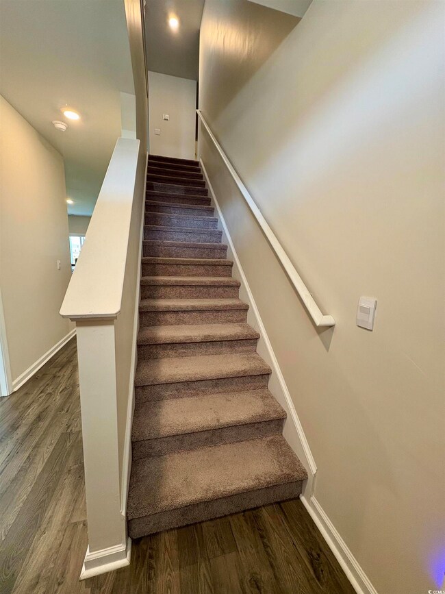 Stairway with wood finished floors and recessed lighting