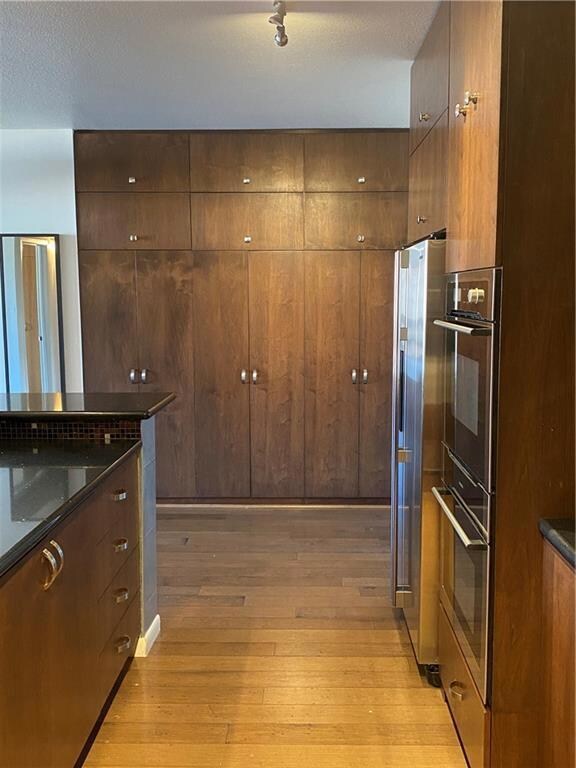Kitchen with light wood-style floors, dark stone 