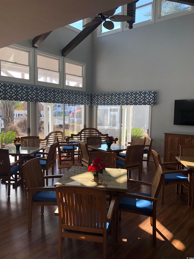 Dining space with a towering ceiling, plenty of natural light, wood finished floors, and ceiling fan