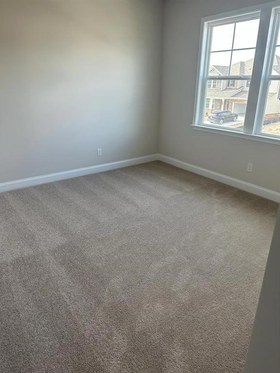 Carpeted spare room featuring baseboards