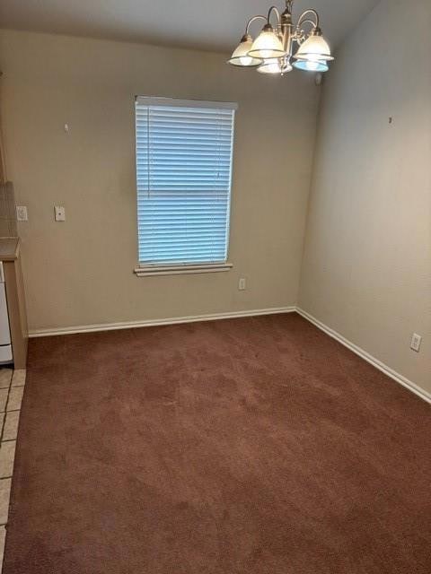 Unfurnished room featuring a chandelier and carpet floors