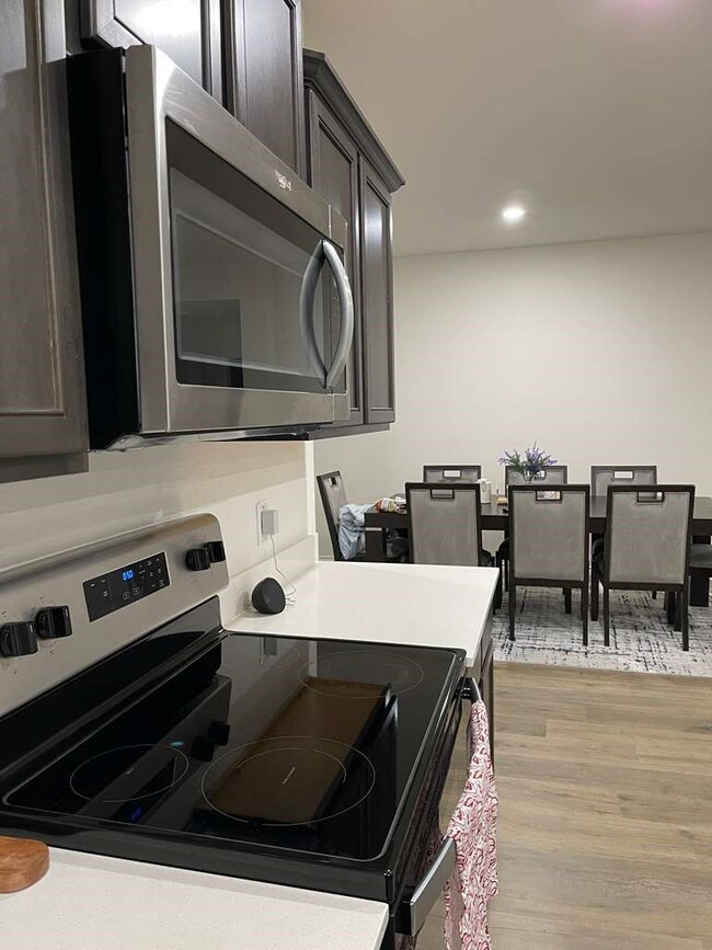 Kitchen with appliances with stainless steel finishes, light wood finished floors, light countertops, and recessed lighting