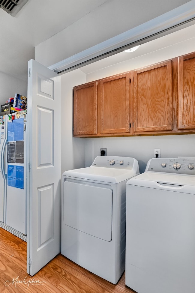 Laundry area featuring cabinet space, light wood-type flooring, and independent washer and dryer