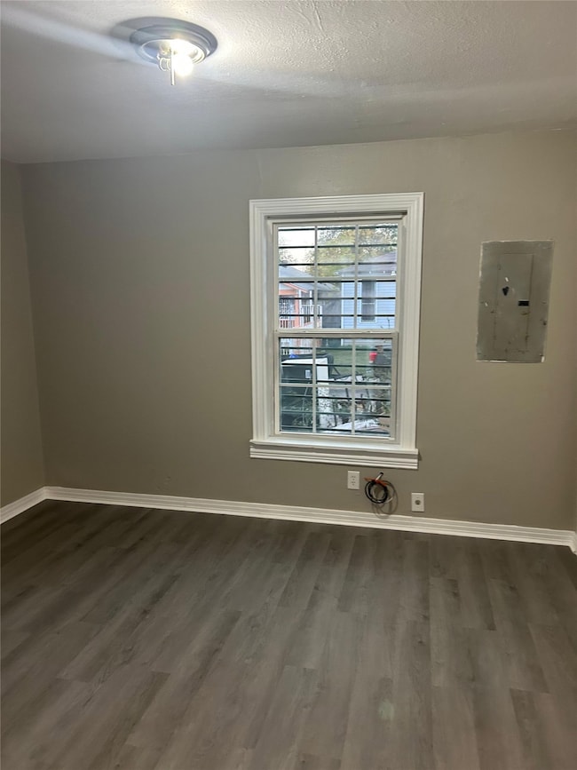 Empty room featuring electric panel, dark wood-style floors, and a textured ceiling