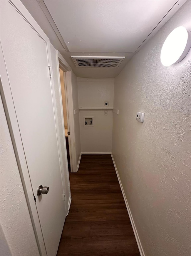 Hallway featuring visible vents, dark wood-type fl
