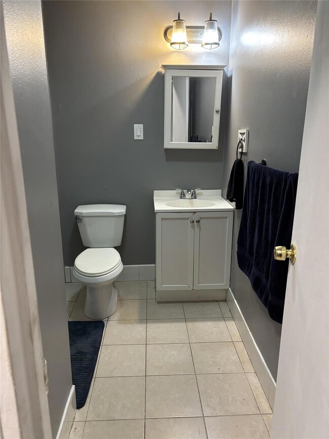 Bathroom with toilet, vanity, baseboards, and tile patterned flooring