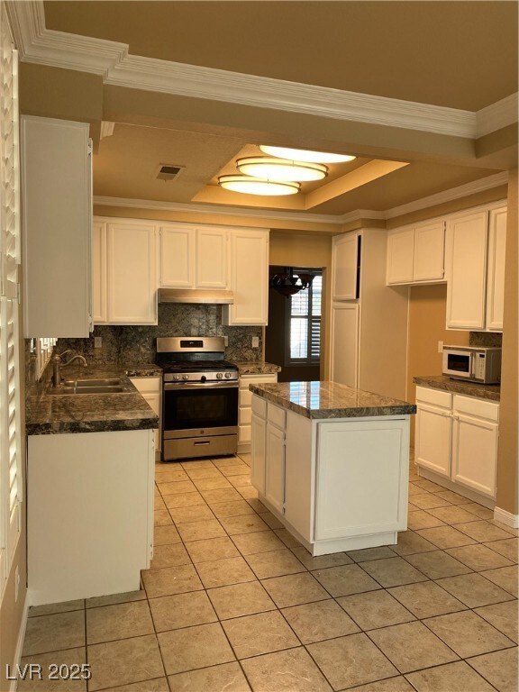 Kitchen with white cabinetry, ornamental molding, range, decorative backsplash, and light tile patterned flooring