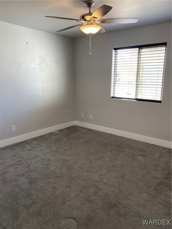 Carpeted spare room featuring ceiling fan