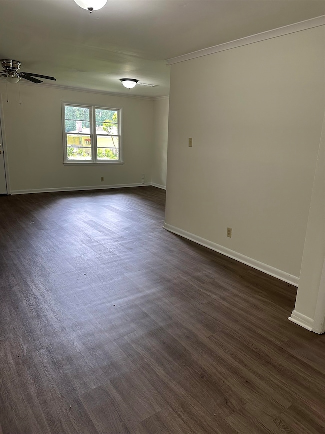 Unfurnished room featuring a ceiling fan, crown molding, and dark wood-style floors
