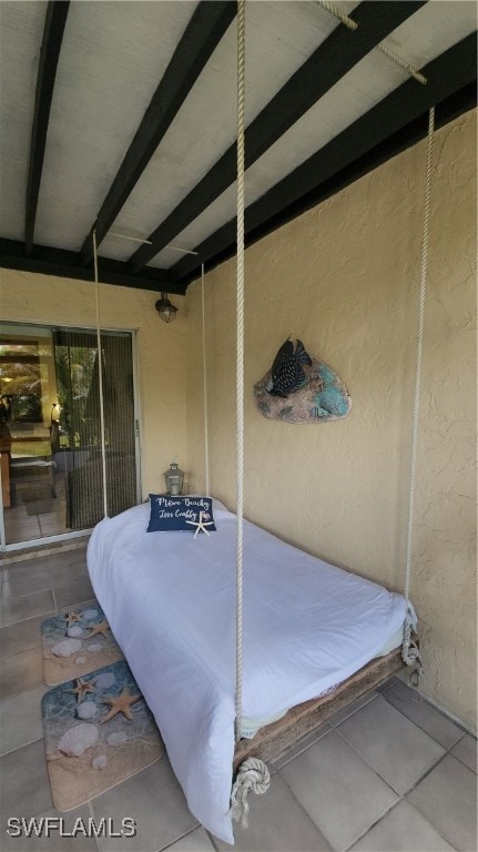Bedroom featuring a textured wall and beam ceiling