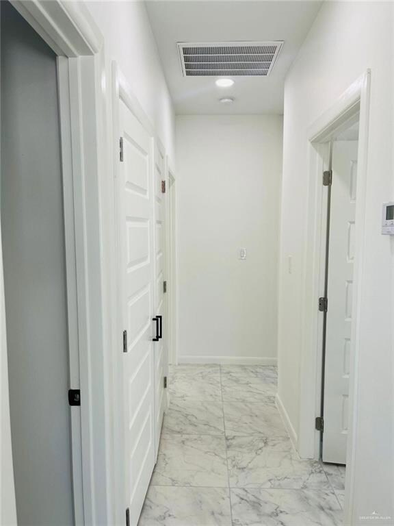Hall featuring light marble finish floors and baseboards