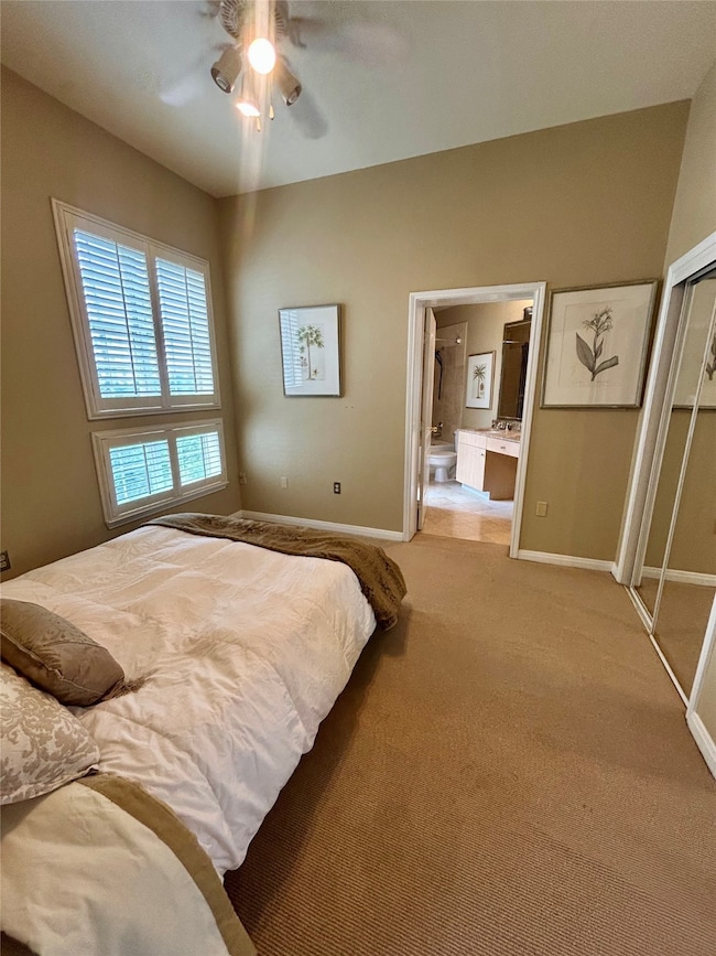 Bedroom with carpet floors, a closet, ceiling fan, and ensuite bathroom