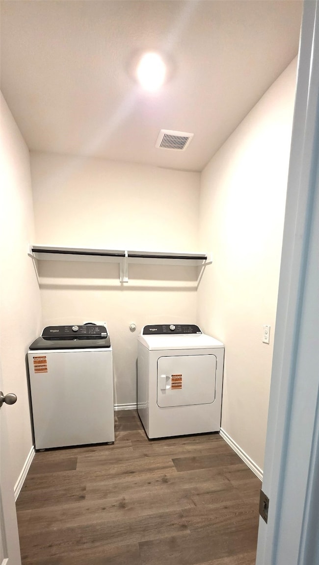 Washroom with dark wood-type flooring and washing machine and dryer