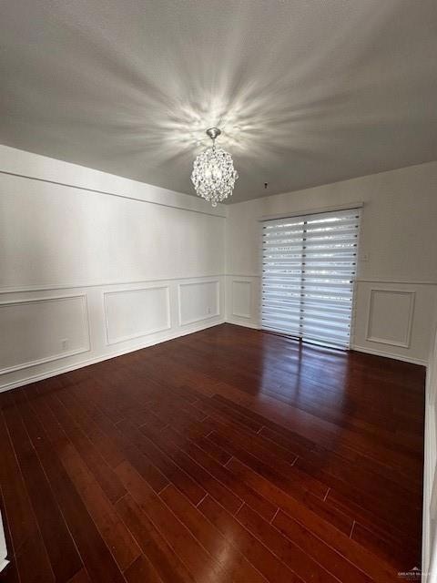 Spare room featuring dark hardwood / wood-style flooring and a chandelier