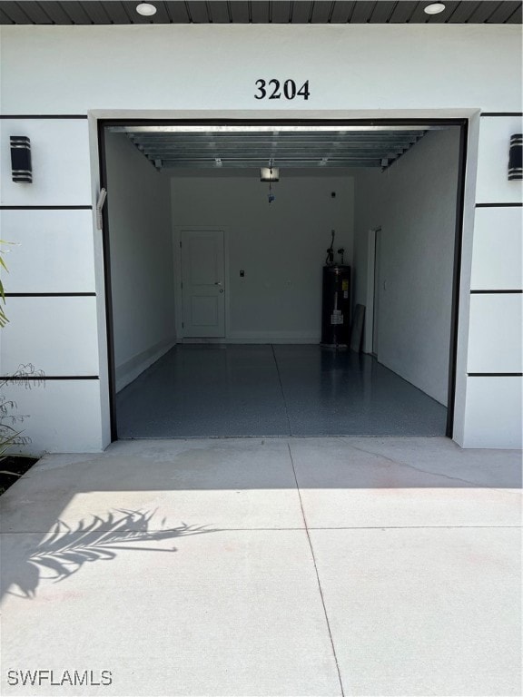 Garage with water heater, driveway, and a garage door opener