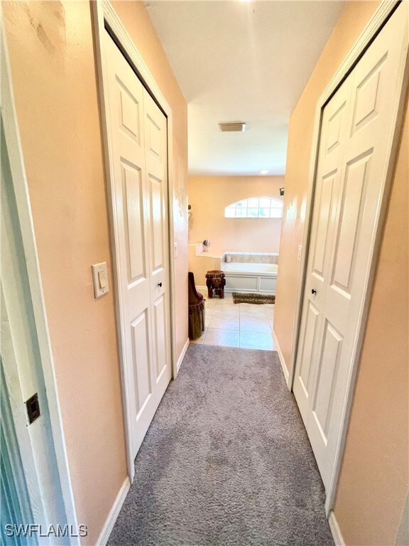 Hall with baseboards, carpet floors, visible vents