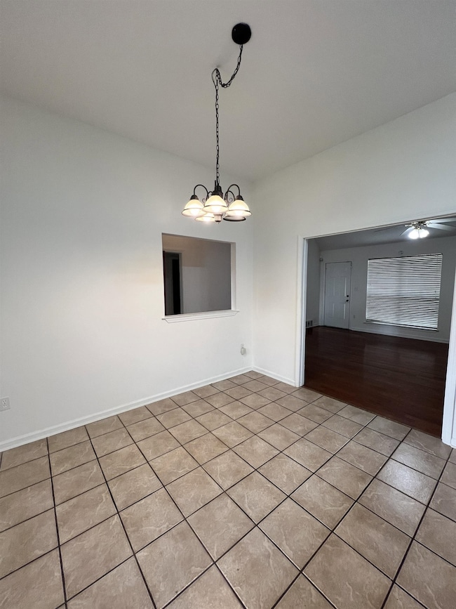 Tiled spare room featuring a chandelier and a ceiling fan