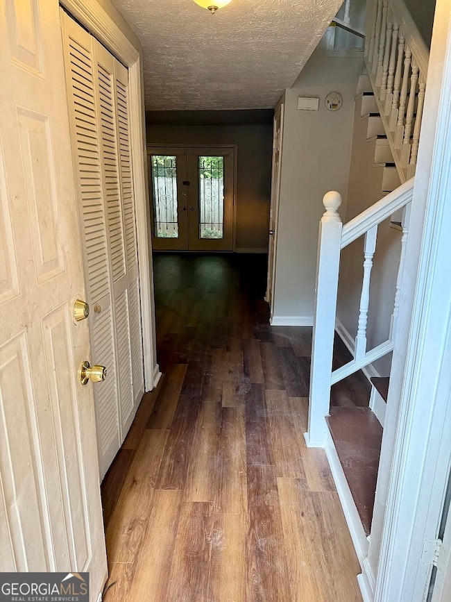 Spacious living room featuring rich flooring, a cozy brick fireplace, and double French doors leading to the private patio.