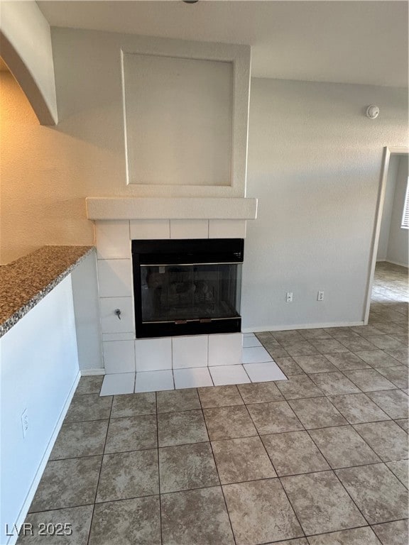 Room details with a tile fireplace, baseboards, an