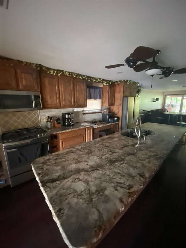 Kitchen featuring ceiling fan, fridge, sink, backs