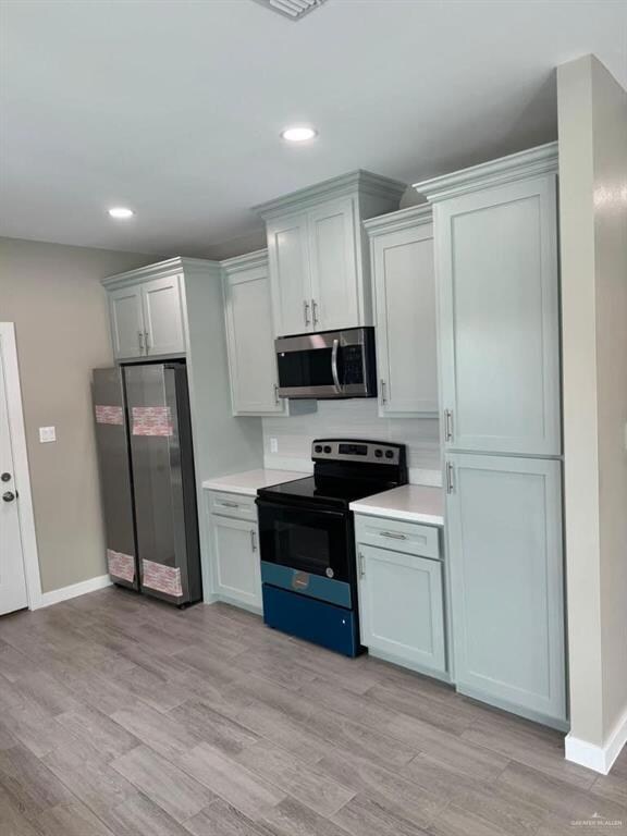 Kitchen featuring appliances with stainless steel finishes, light countertops, recessed lighting, and light wood-style flooring