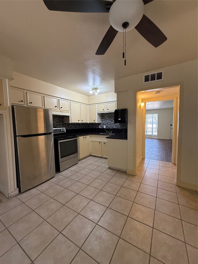 two-story townhouse with a mix of brick and siding exterior. It features a small front yard with a concrete path leading to the entrance. Large windows on the second floor and a neatly landscaped area enhance its curb appeal.