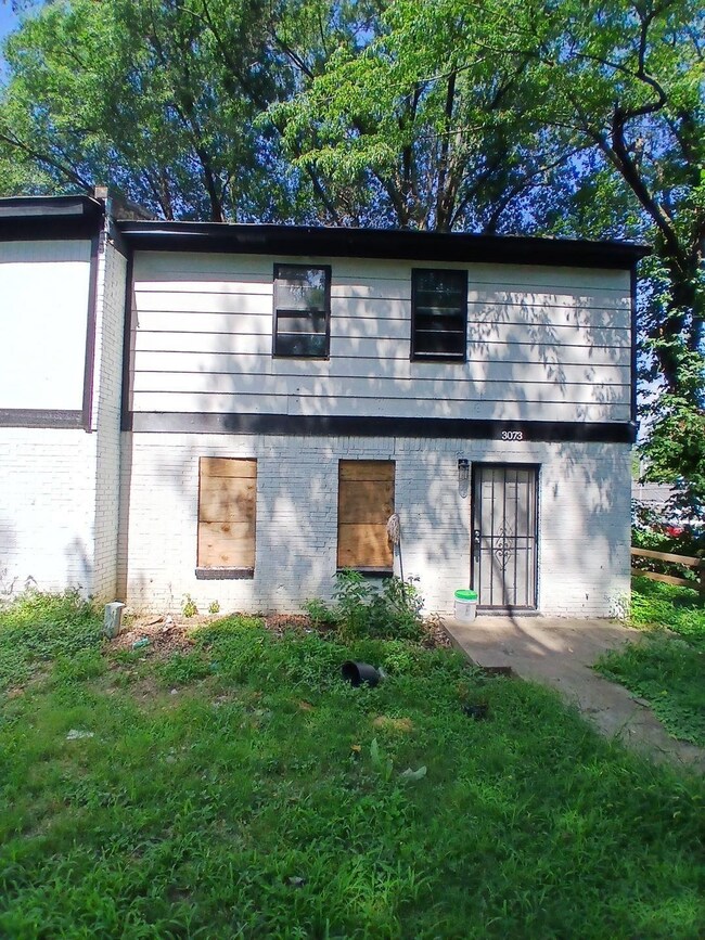 Rear view of property featuring brick siding and a yard
