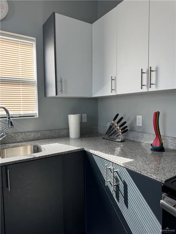 Kitchen featuring a sink, white cabinets, and light countertops