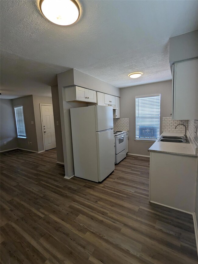 Kitchen featuring white appliances, a sink, a tex