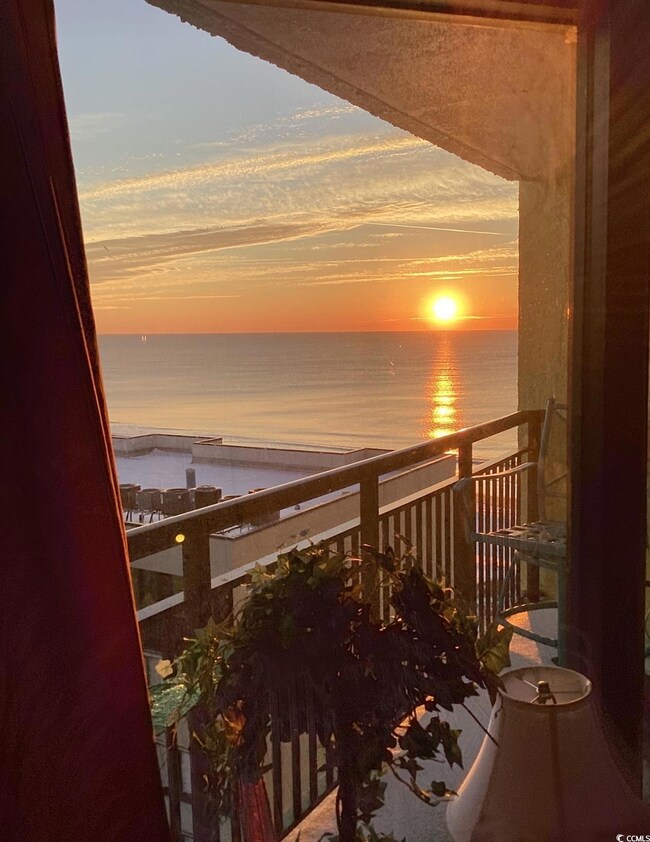 Balcony at dusk featuring view of water and beach