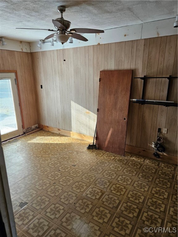 Spare room featuring a textured ceiling, wooden wa