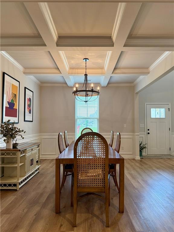 Dining room featuring plenty of natural light, beam ceiling, a chandelier, wood finished floors, and a decorative wall