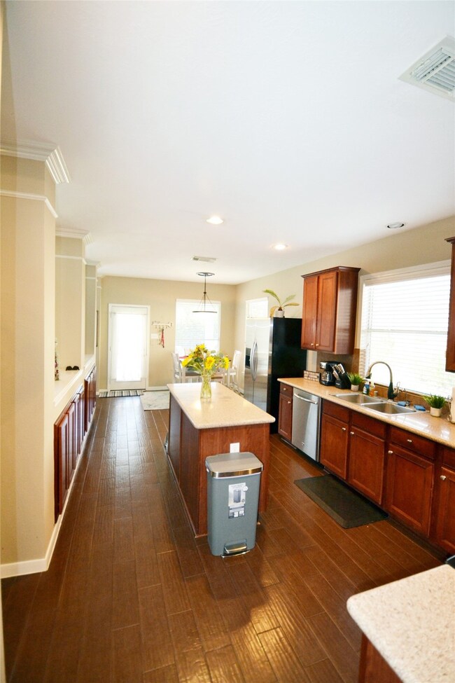 Kitchen with breakfast nook, wood-like tile flooring, stainless steel appliances.