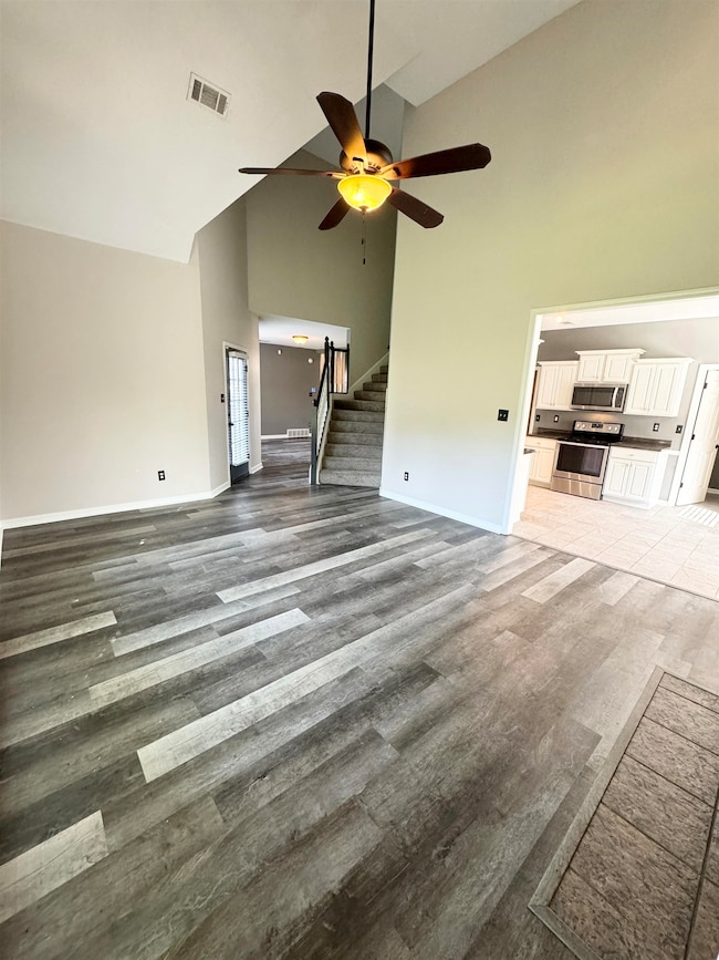 Unfurnished living room with high vaulted ceiling,