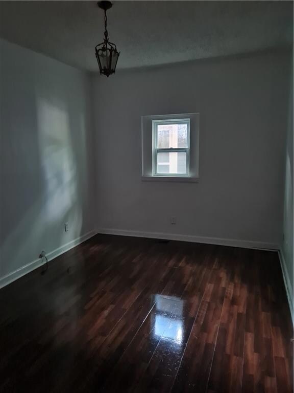 Spare room with dark wood-style floors and baseboards