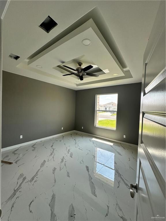 Unfurnished room featuring tile floors, ceiling fan, and a tray ceiling