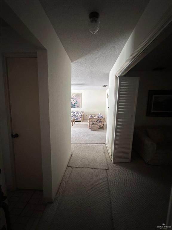 Hall with carpet floors and a textured ceiling
