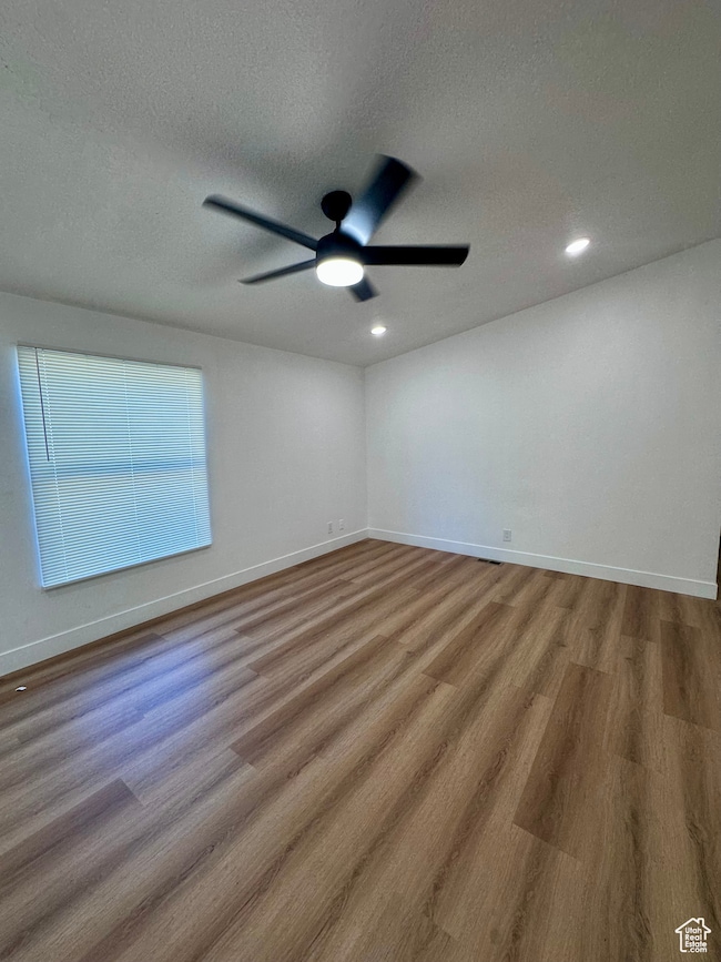 Unfurnished room with a textured ceiling, wood finished floors, and ceiling fan