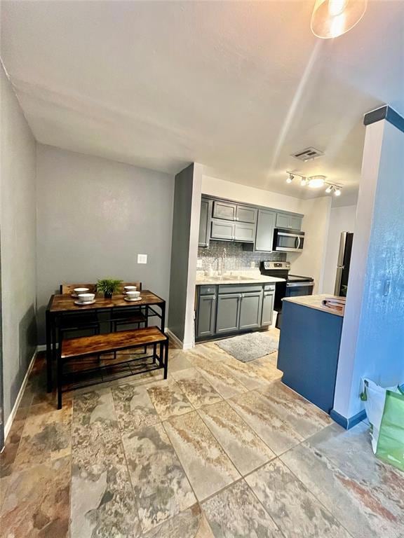 Kitchen with backsplash, light countertops, stainless steel appliances, and gray cabinetry