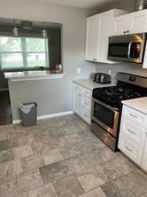 Kitchen with white cabinets, stainless steel appliances, and light tile patterned flooring