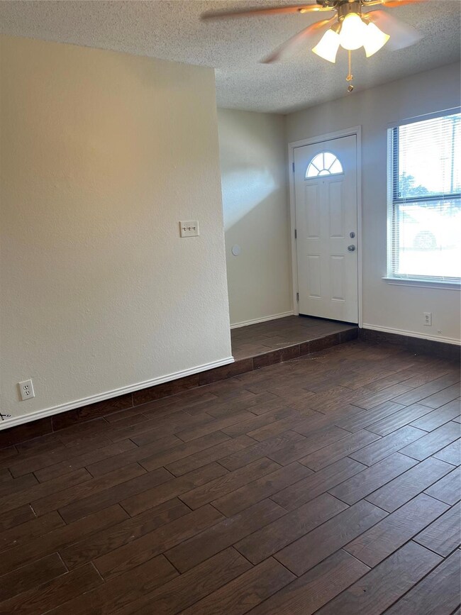 Foyer entrance with a textured ceiling, dark wood-