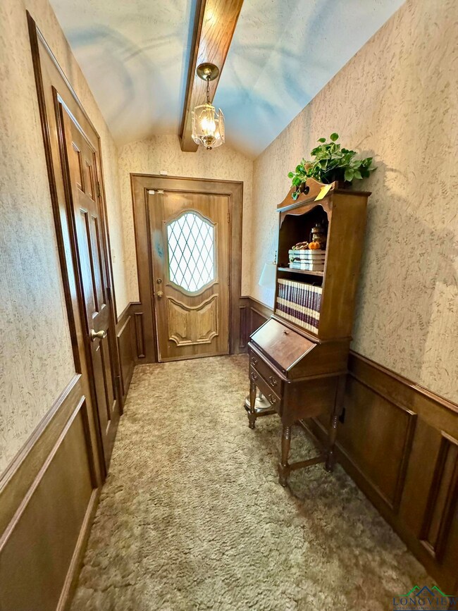 Entryway featuring vaulted ceiling, wainscoting, and carpet