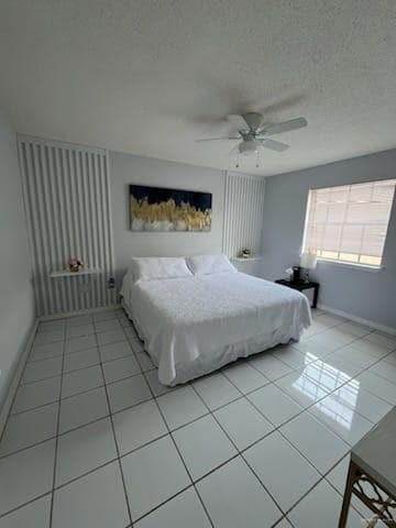 Bedroom with light tile patterned flooring, ceiling fan, and a textured ceiling