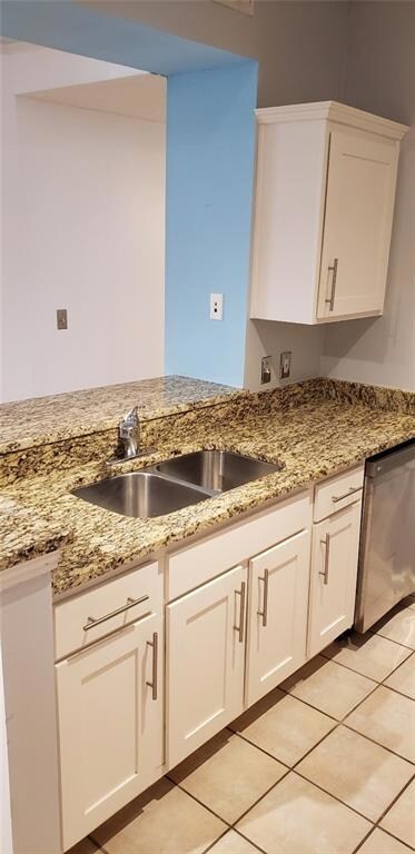 Kitchen featuring dishwasher, white cabinetry, light stone countertops, and light tile patterned floors