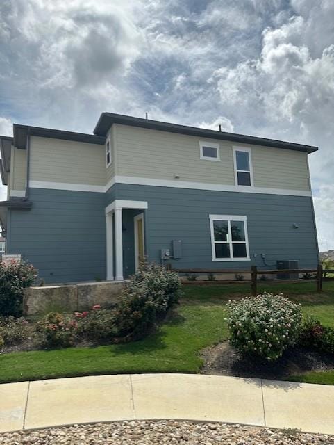 Rear view of house with a lawn and central AC