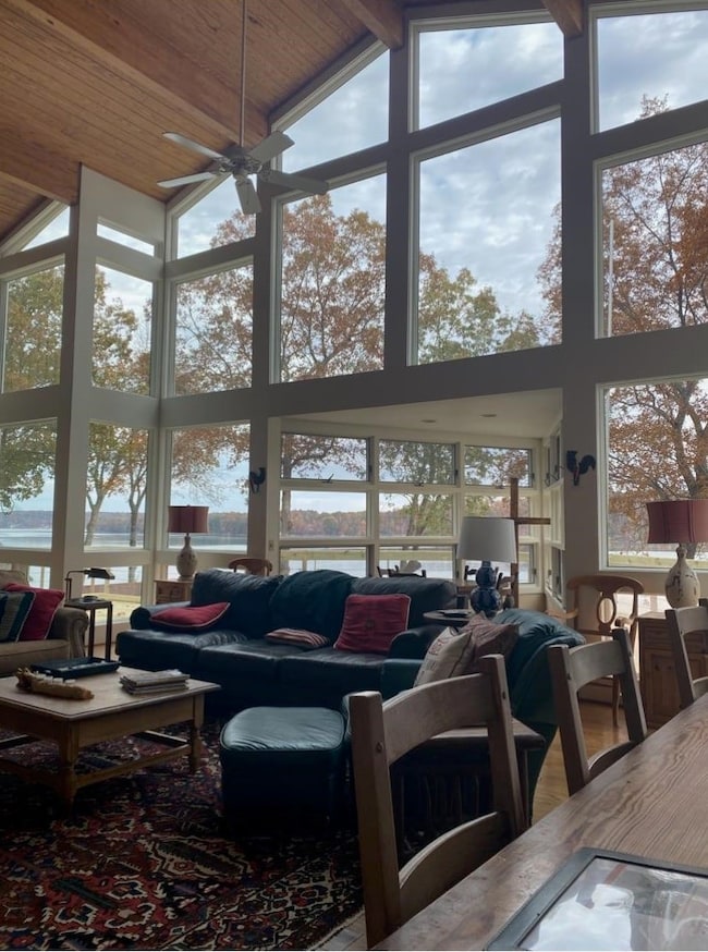 Living area with high vaulted ceiling, plenty of natural light, and a ceiling fan