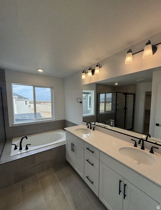 Bathroom with double vanity, a garden tub, a shower stall, and plenty of natural light