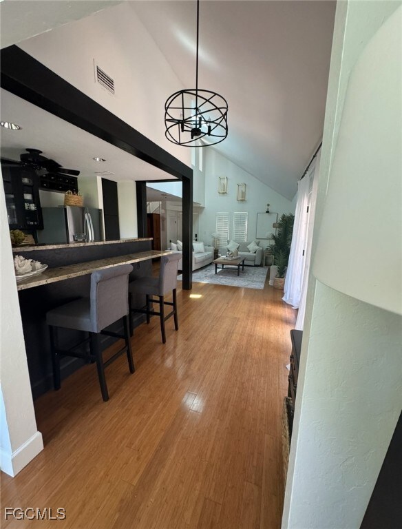 Kitchen into Living room with light wood-style flooring, a chandelier, and high vaulted ceiling