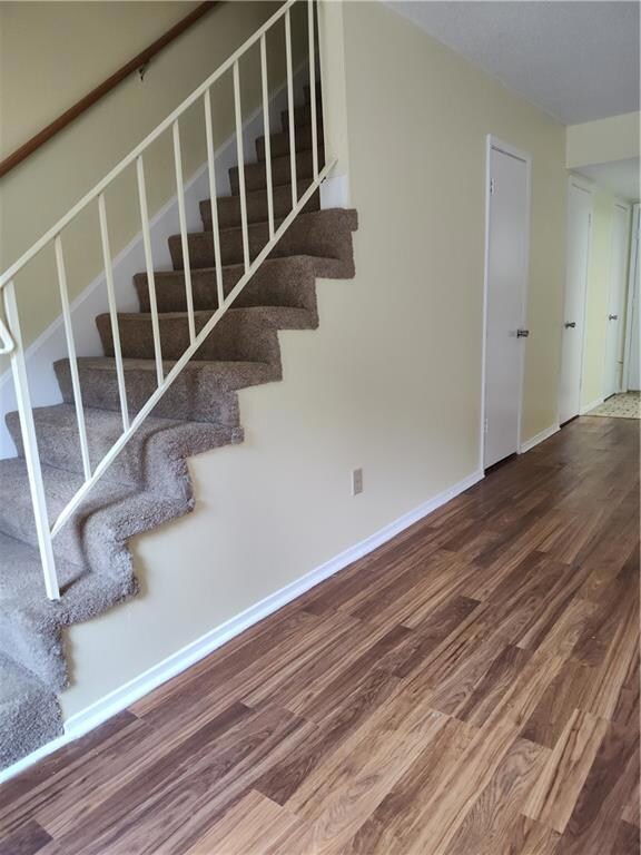 Stairway with wood finished floors and baseboards